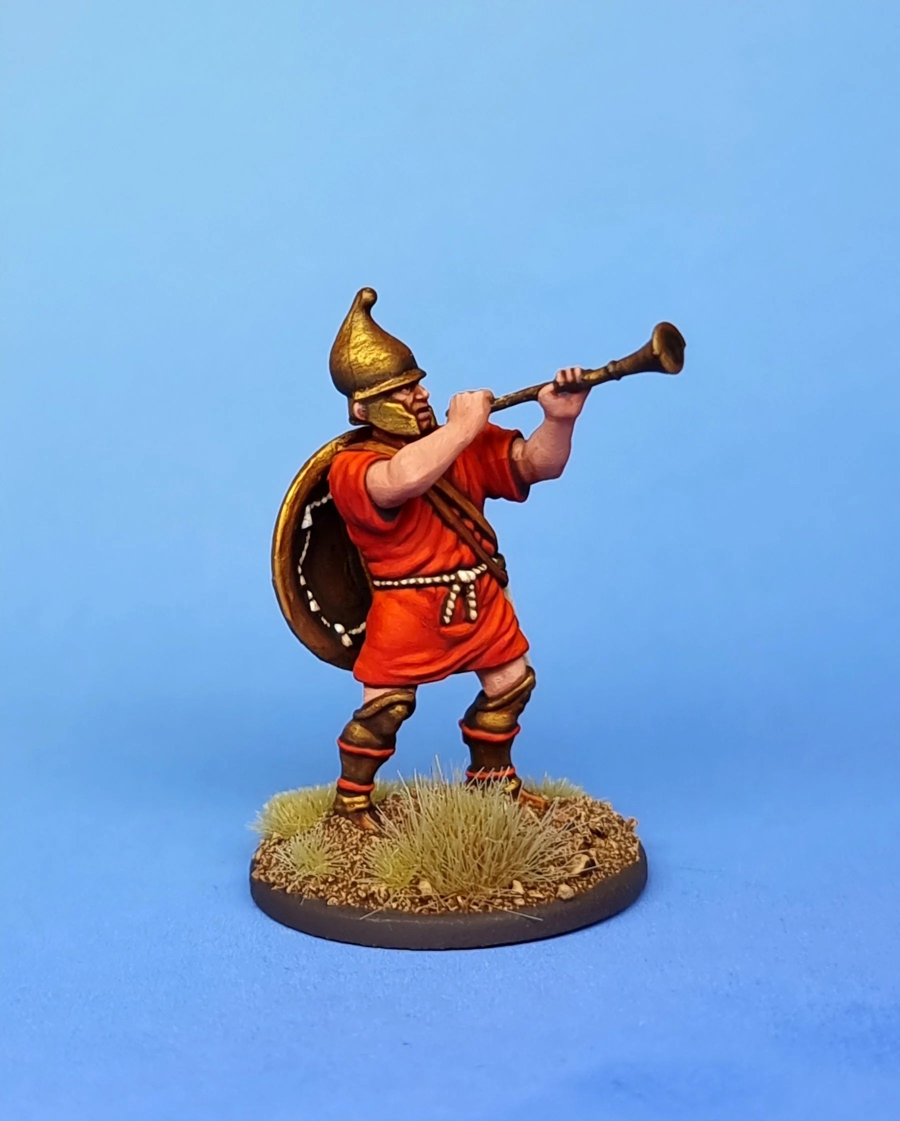 Close-up view of a painted 28mm Macedonian musician miniature blowing a bronze trumpet