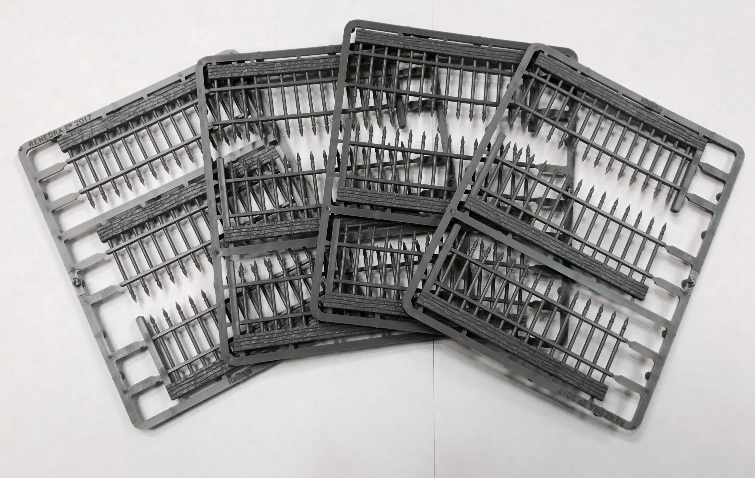 Four unassembled gray hard plastic sprue frames for the Renedra Railings kit displaying multiple iron-style fence segments