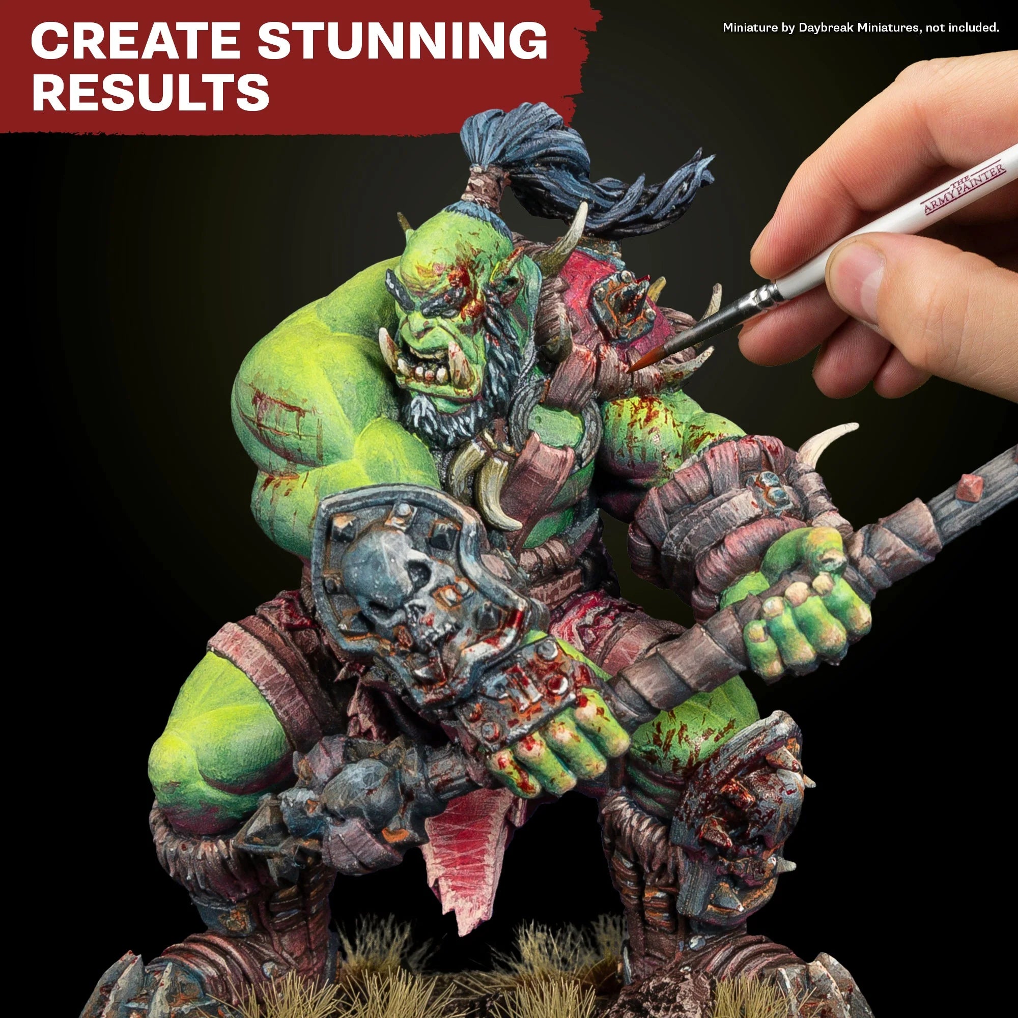 Close-up application showing a brush painting a highly detailed green-skinned orc miniature with crisp highlighting.
