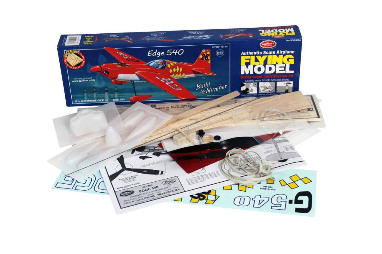 Guillow's 1/14 scale Zivko Edge 540 balsa wood model kit contents showing laser-cut parts, plans, and plastic cowl.