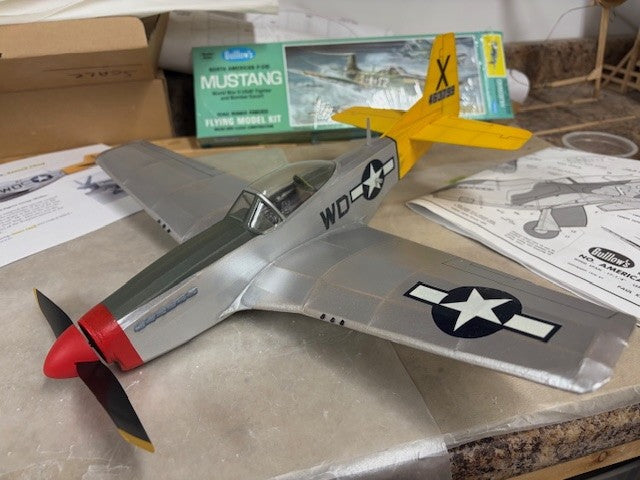 Assembled Guillow's P-51D Mustang balsa model airplane with yellow tail markings on display.