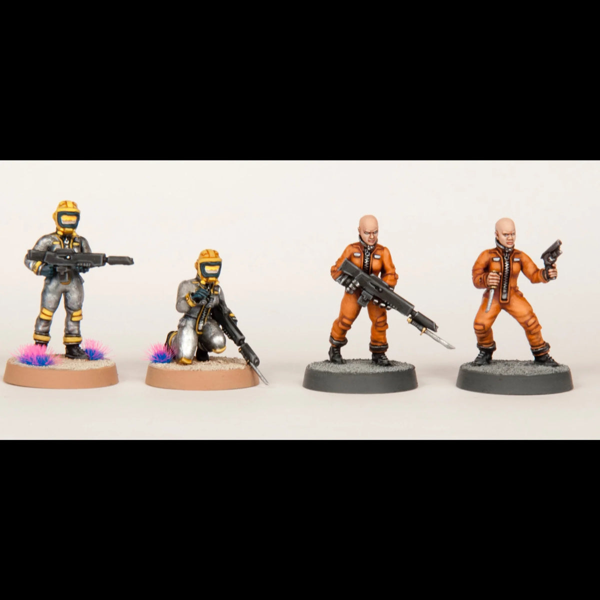 Four painted 28mm female miniatures displayed in space suits and orange convict jumpsuits
