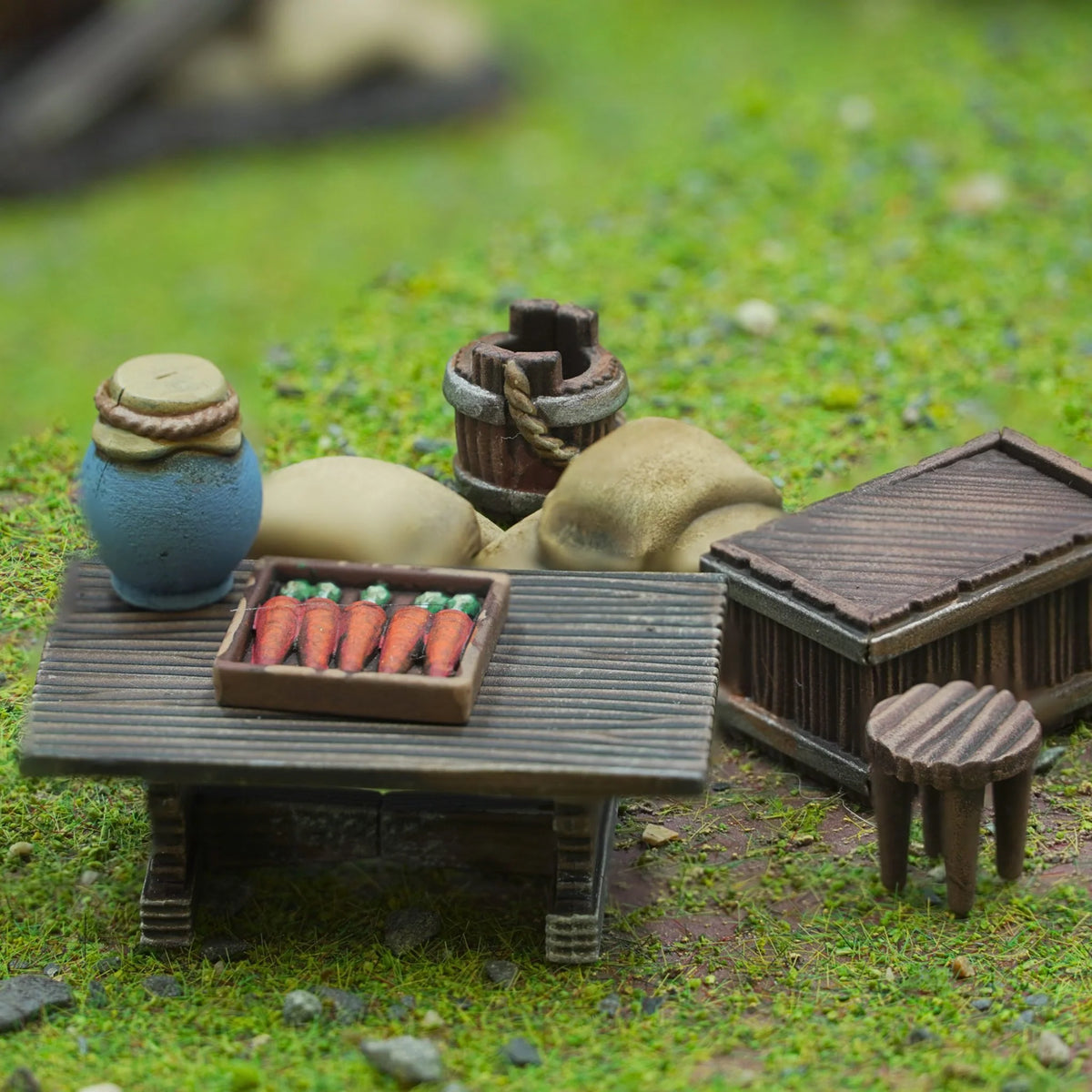 Painted wooden trestle table display with crate of carrots, ceramic pitcher, bucket, and storage chest 