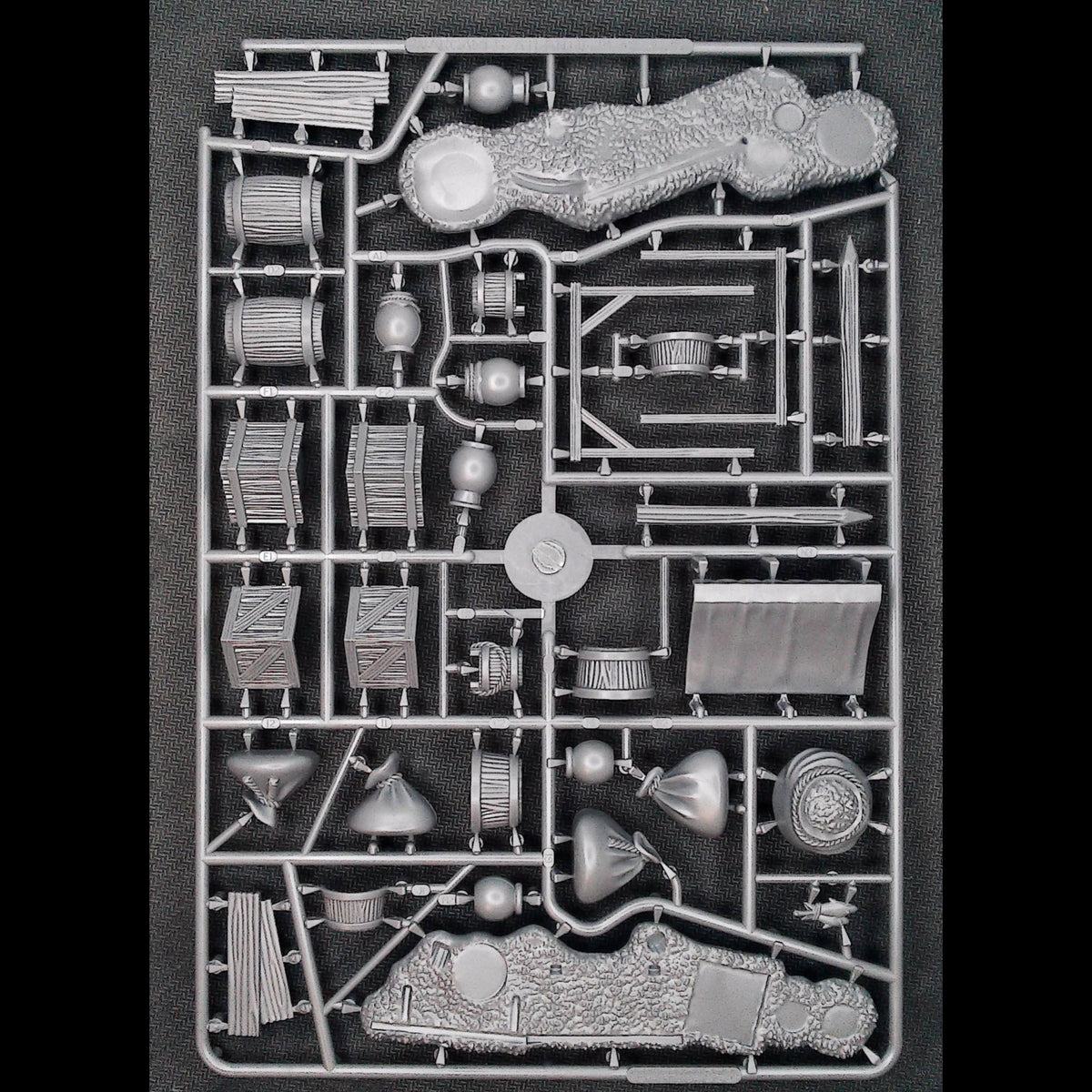 Front perspective of unpainted gray plastic component sprue showing barricade bases, stall roof, and scatter bits 