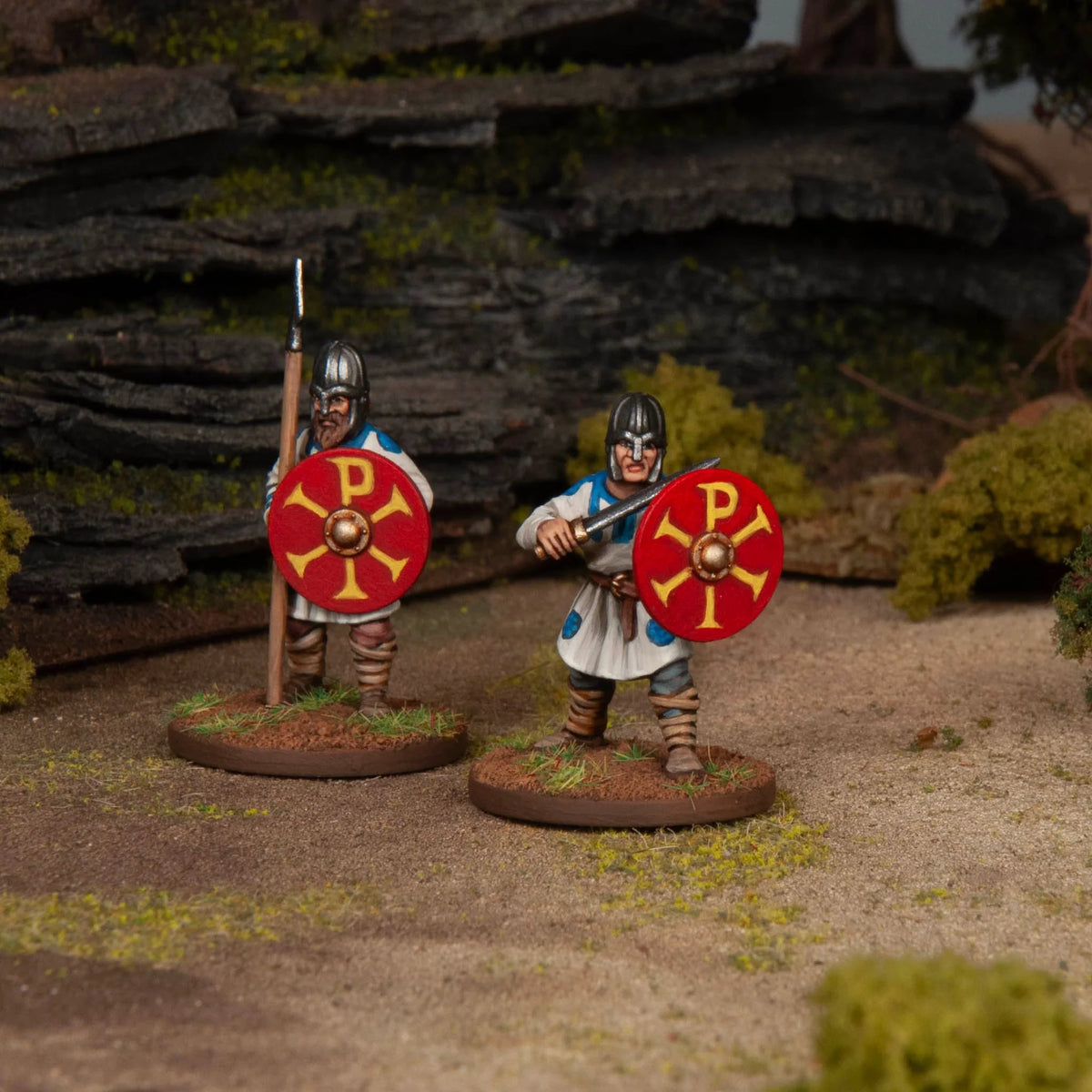 Two painted unarmored Late Roman soldiers wearing spangenhelm helmets with Chi-Rho painted shields 