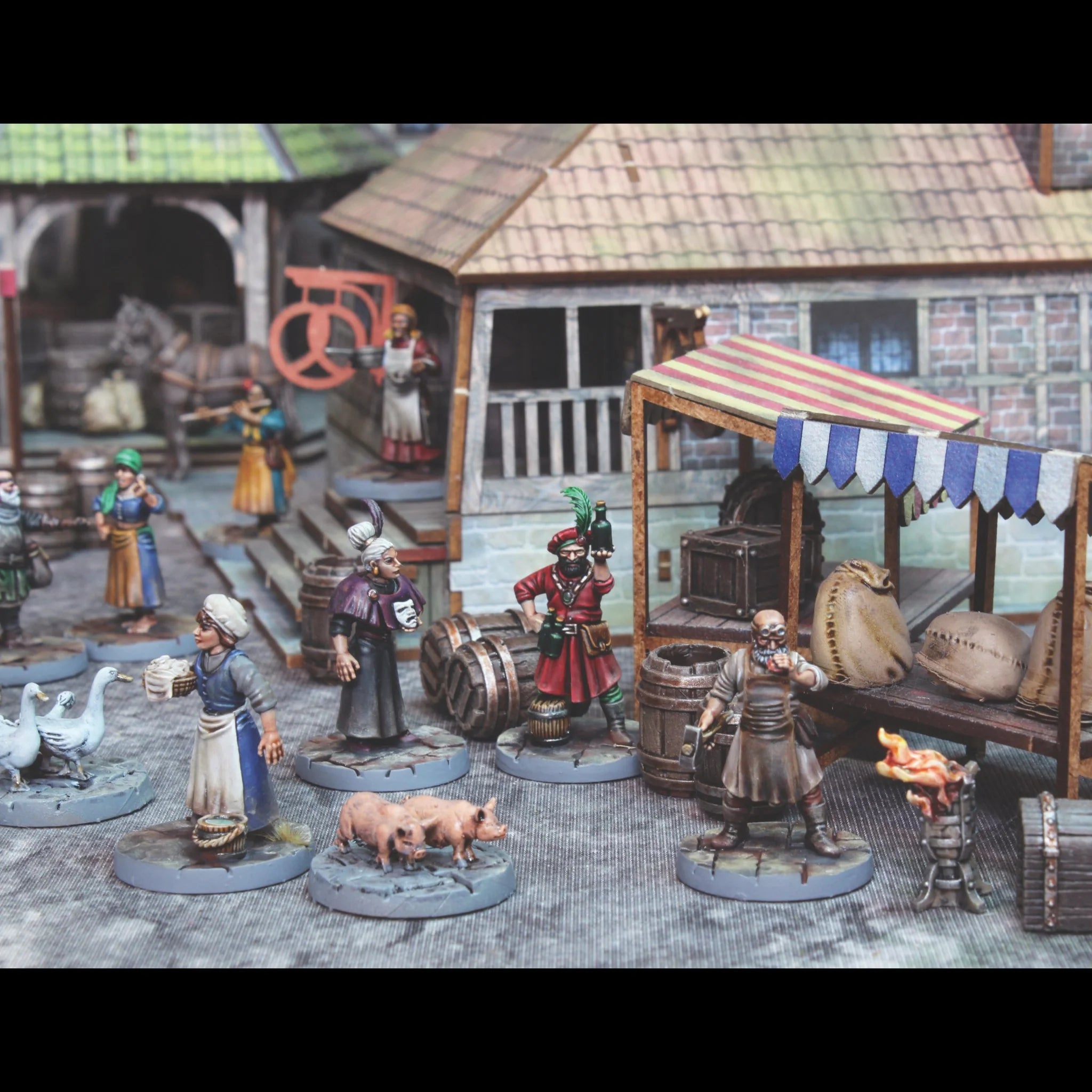 Assembled and painted fantasy villager miniatures standing outside medieval buildings and market stalls