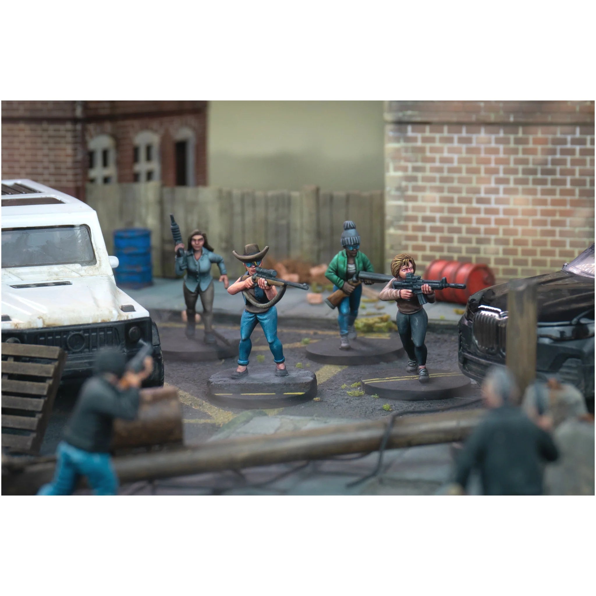 Four painted survivor miniatures taking cover and firing down an urban street