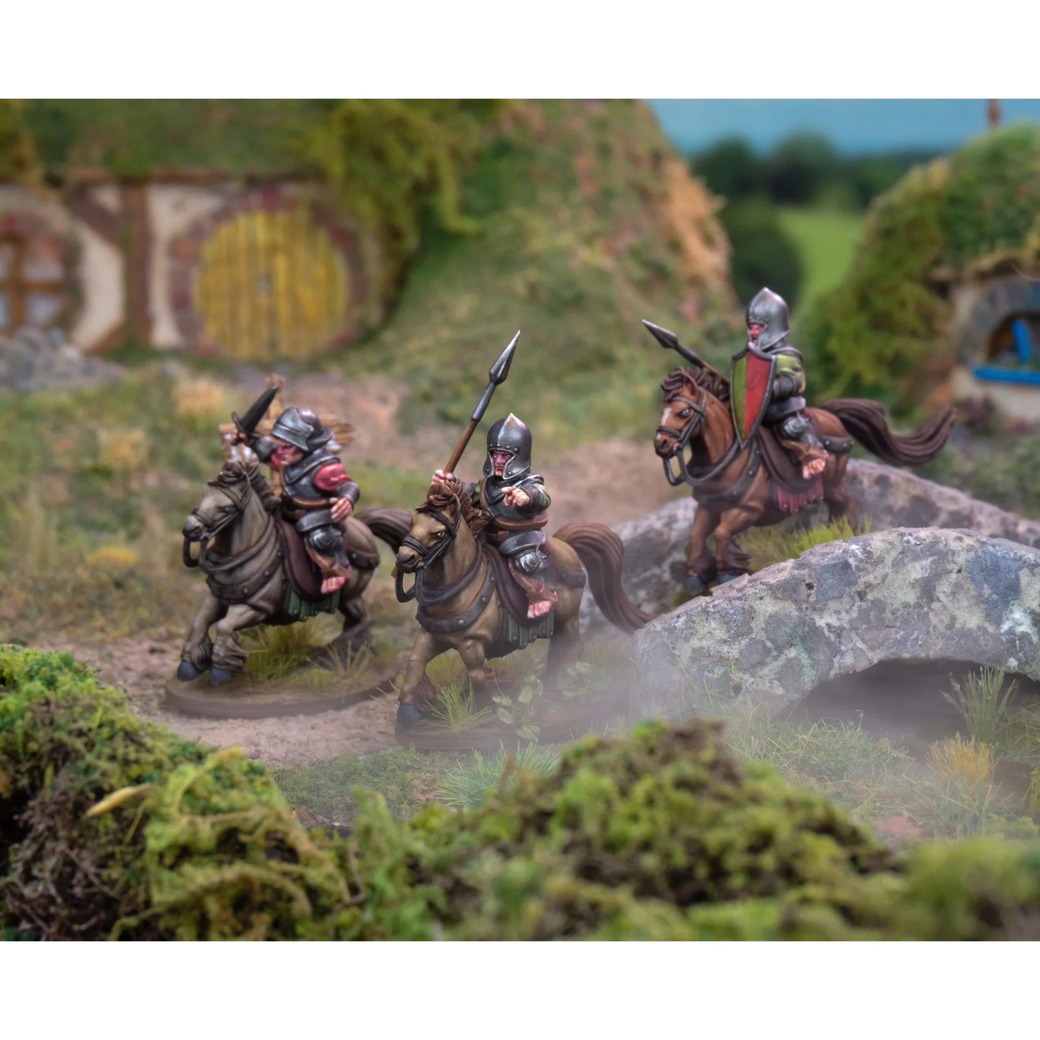 Three painted halfling cavalry miniatures crossing a small stone bridge in a fantasy countryside