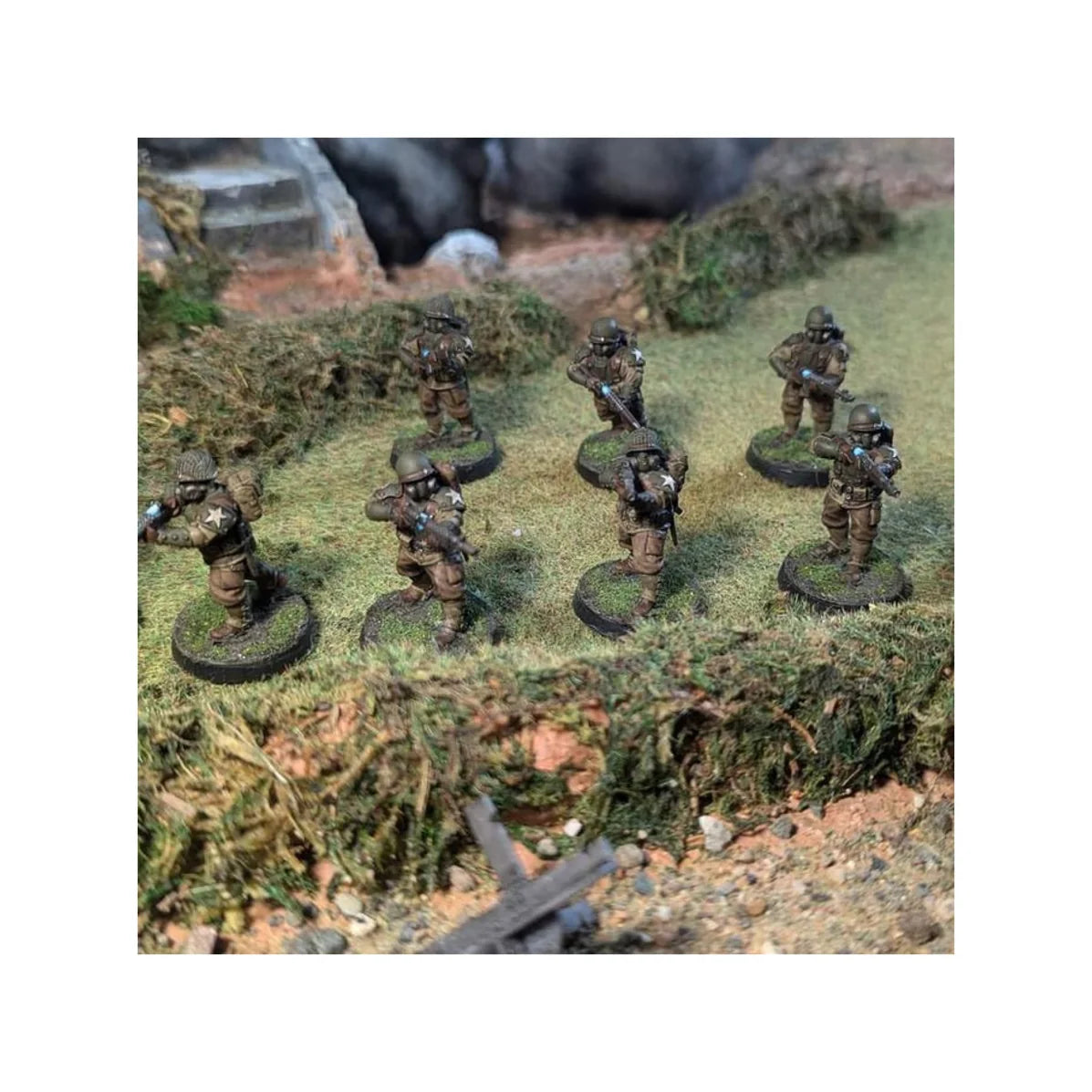 Seven painted 28mm United States dieselpunk infantry figures advancing through a grass field