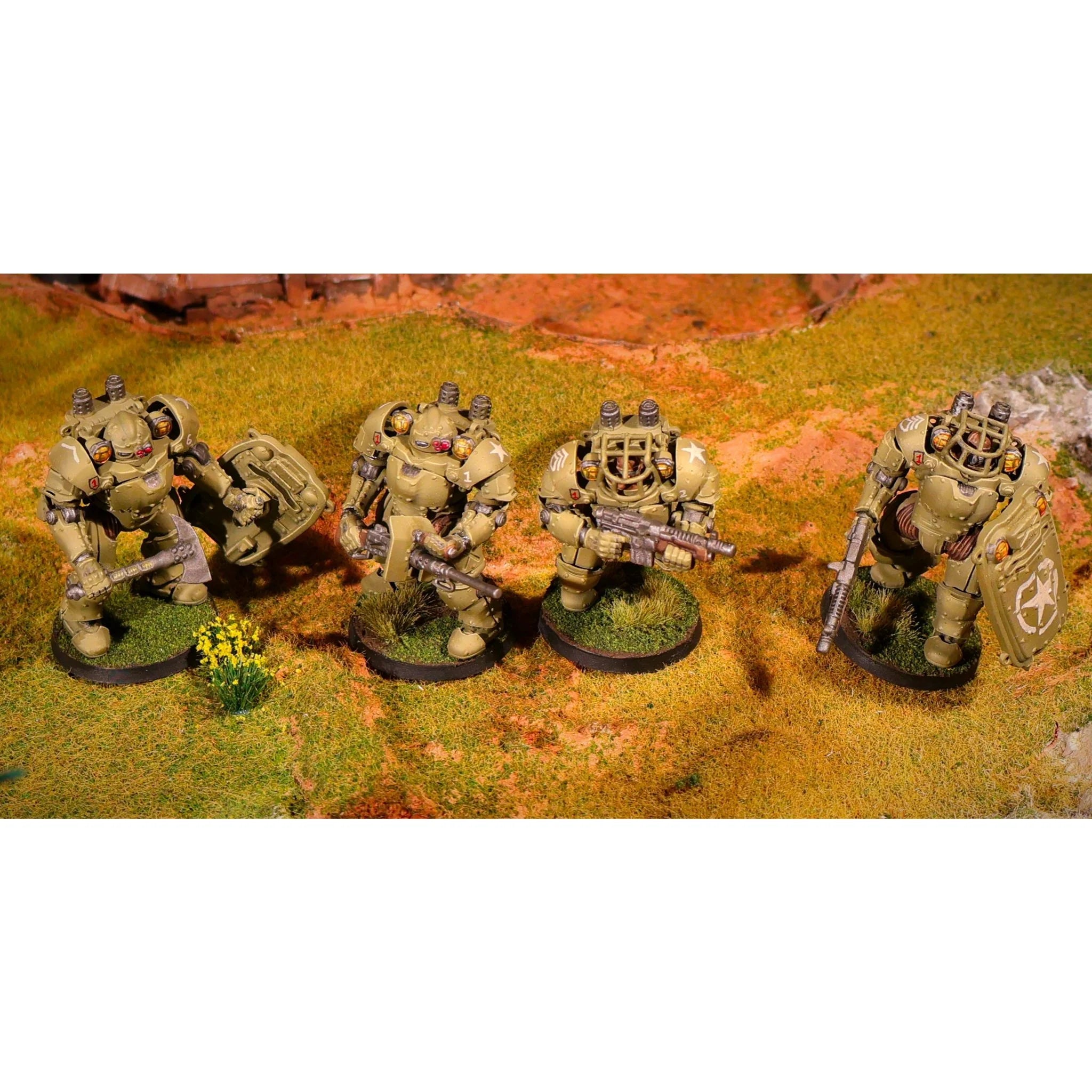 Four painted 28mm United States Badger Hardsuit power armor miniatures on a grassy tabletop