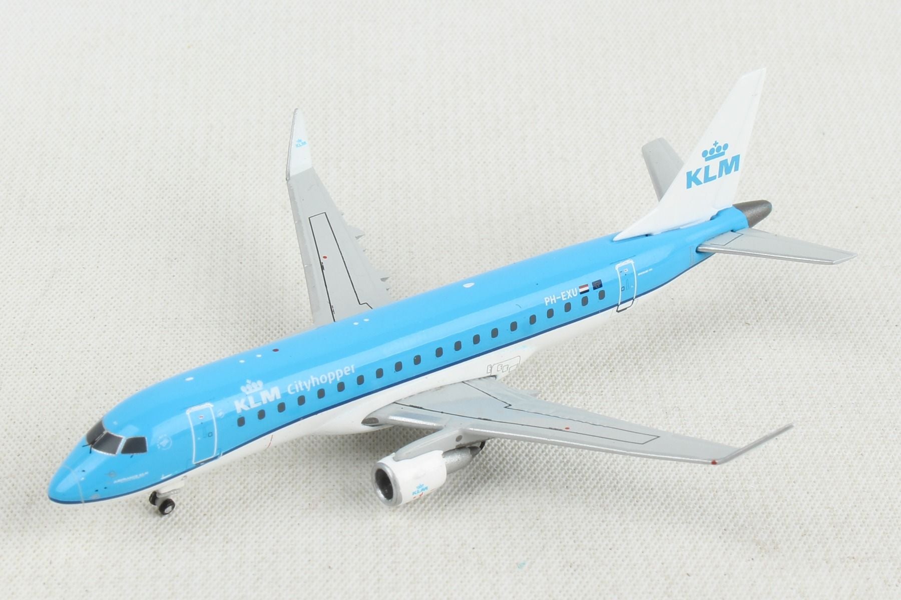 Top down angle of GeminiJets 1 by 400 scale KLM Royal Dutch Airlines Embraer ERJ 175 diecast model PH EXU parked on an airport diorama mat as captured in file